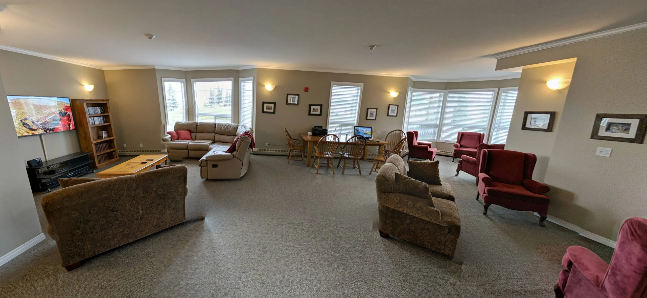 Wide view of the common lounge with sofas, a TV and armchairs